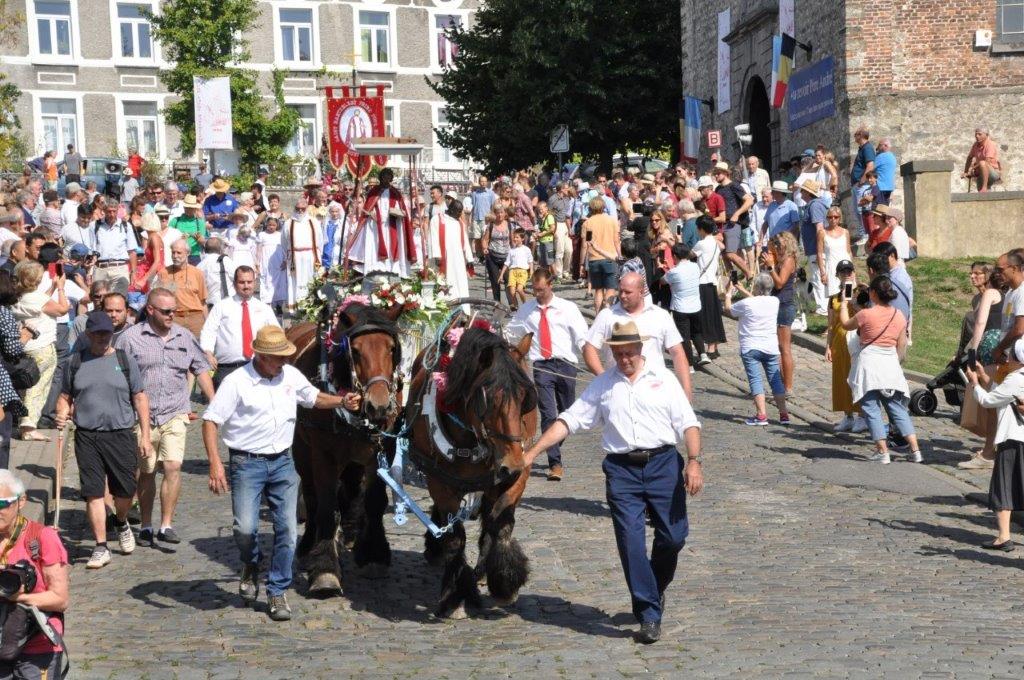 Procession St Bathélémy 2019 : début de la procession devant le porche de l'église. Une grande foule regarde les chevaux de trait