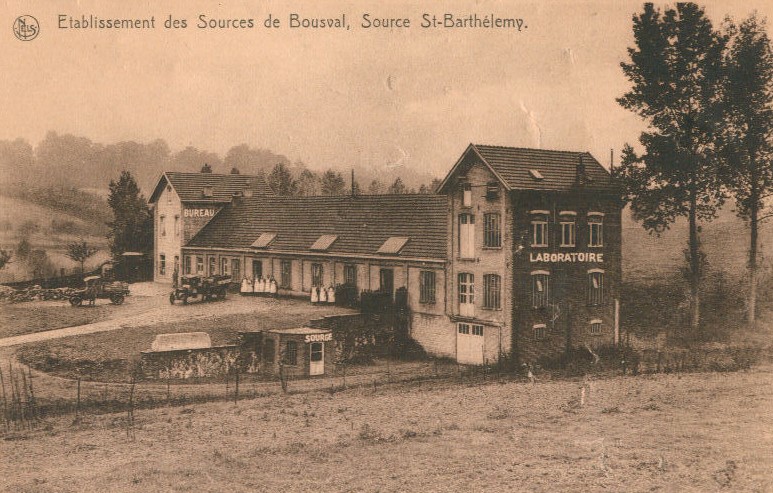 Établissement des Sources de Bousval vers 1930 : l'usine avec de part et d'autre une aile sur laquelle est indiqué à la peinture "laboratoire" et sur l'autre "bureau". Juste à côté, un tout petit bâtiment sur lequel est inscrit "source"