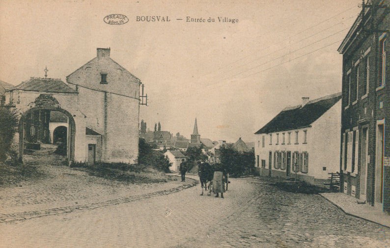 Ferme Saint Martin et des passants dans la rue principale du village de Bousval