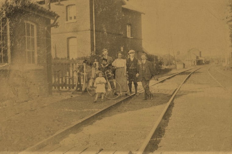 Ancienne carte postale montrant une famille posant près de ligne de chemin de fer n° 141  (passage à niveau de rue de la station, actuelle rue du Grand Arbre)