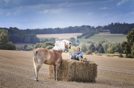 Photo d'une femme sur une botte de foin avec un cheval prise par Laurence Baty