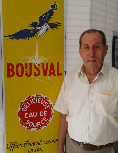 Robert Martin devant une affiche ancienne des "Sources de Bousval" lors de l'Expo 2022